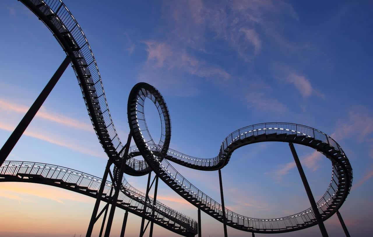 Een rollercoaster met veel lussen en kronkels onder een blauwpaarse hemel.